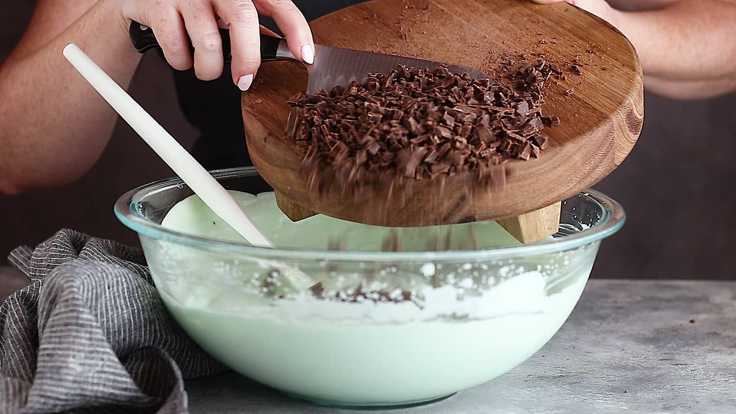 Adding chopped chocolate to mint chocolate chip ice cream base.