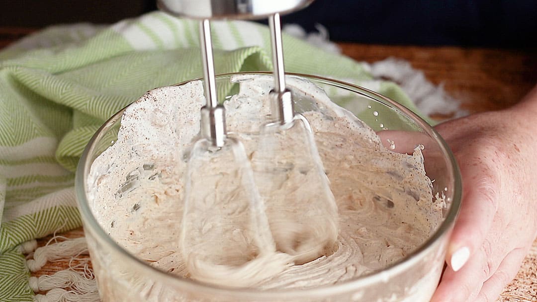 Mixing seasoned sour cream with an electric mixer.