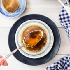 Overhead image of a spoonful of brown butter over a bowl with a blue checkered napkin.
