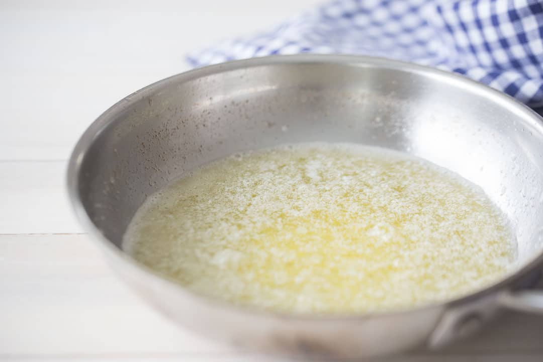 Simmering butter in a small stainless steel skillet.