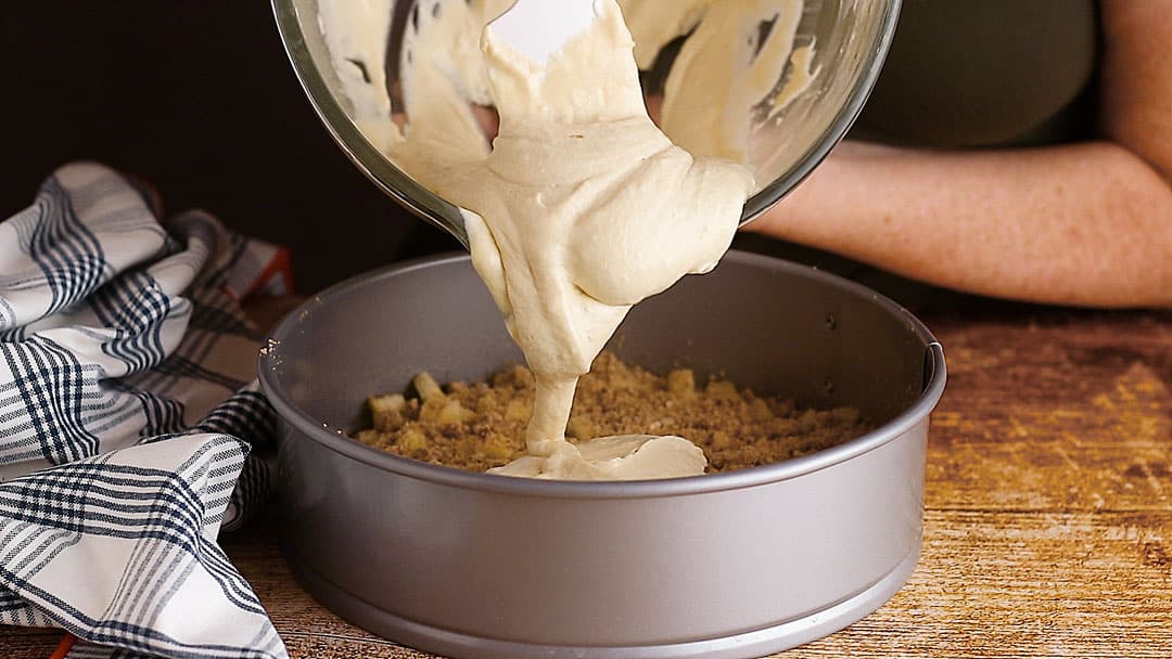 Layering cake batter over apples and cinnamon.