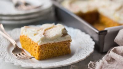 Best pumpkin cake recipe on a white plate with a 9x13 pan in the background.