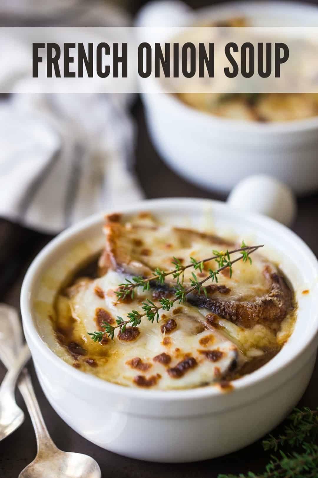 Homemade French onion soup recipe served in ceramic crocks, with melted cheese and fresh thyme, and a text overlay above reading "French Onion Soup."