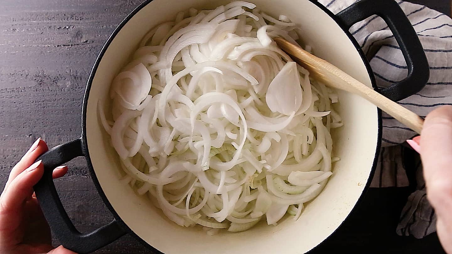 Sliced onions in a cast iron pot for French onion soup.