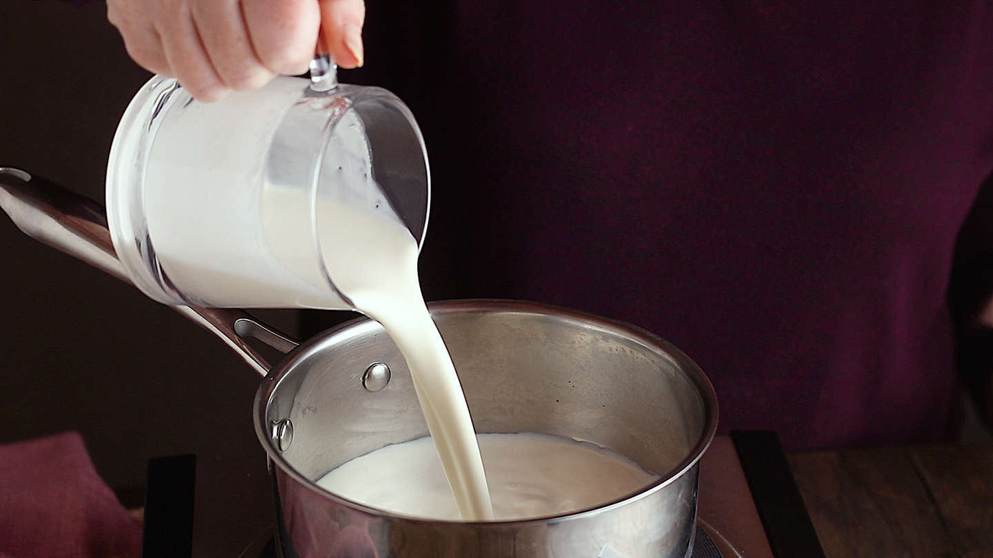 Making panna cotta: Pouring milk into a small pot.