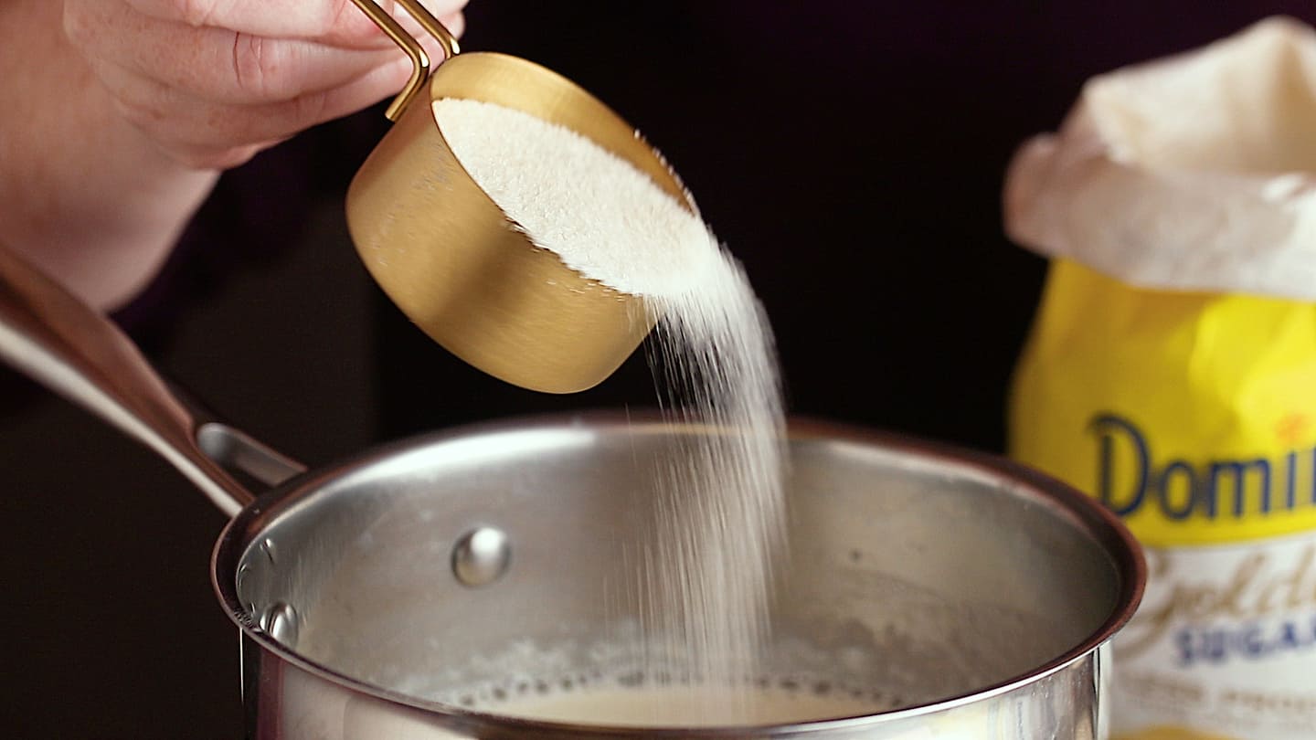 Making panna cotta: Sprinkling sugar into the pot.