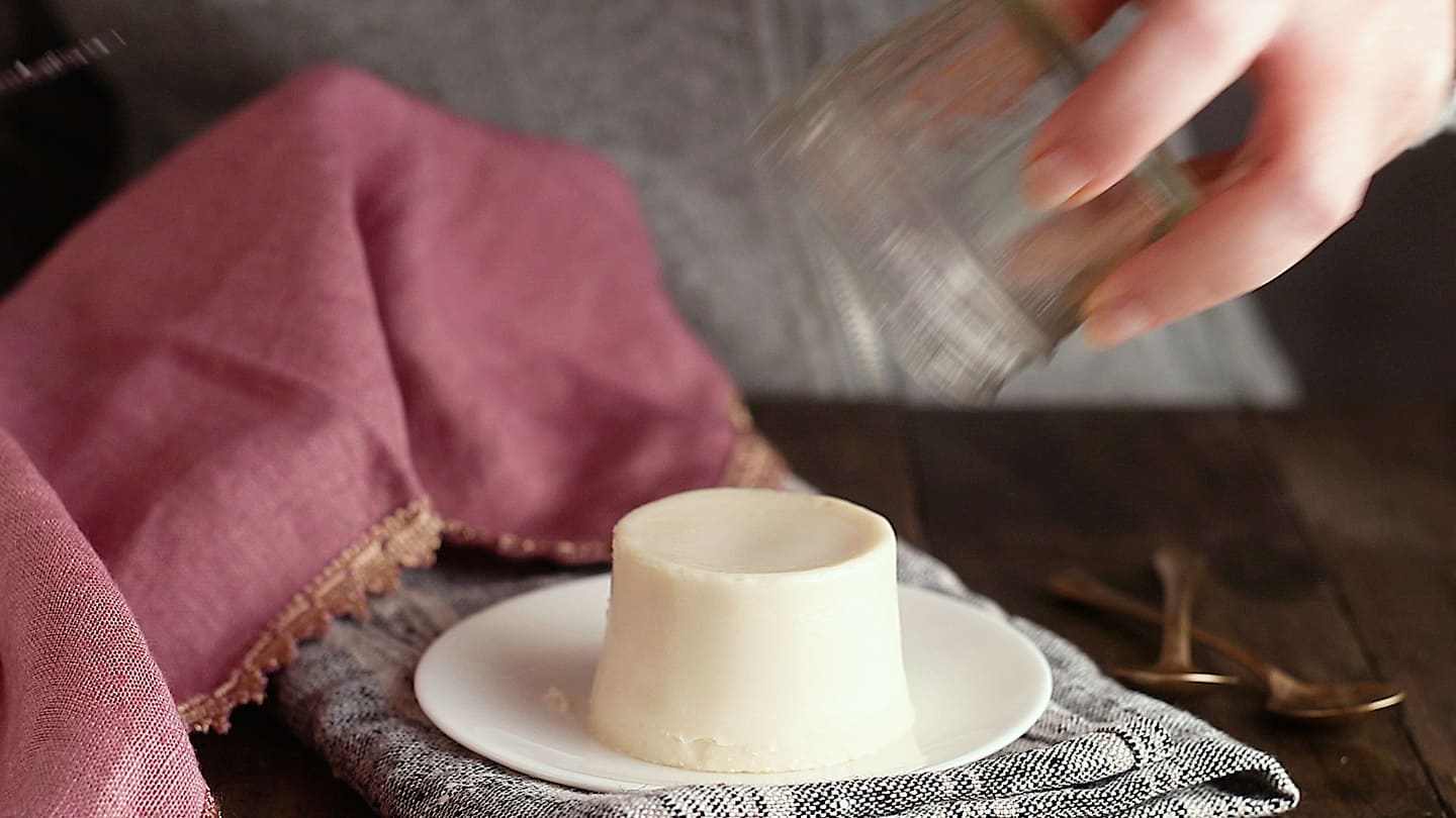 Unmolding chilled panna cotta onto a serving plate.