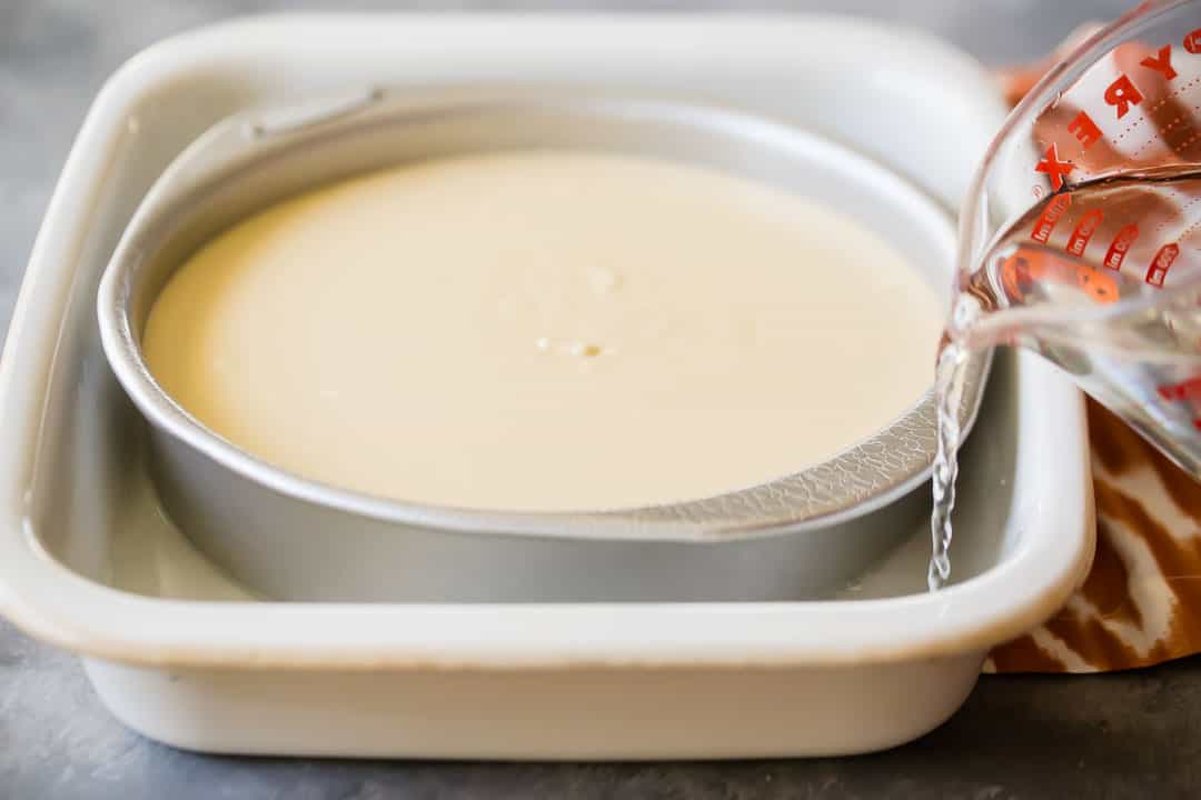 Pouring water around a cheesecake pan to make a water bath.