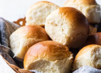 Close up image of a basket of freshly baked soft dinner rolls.