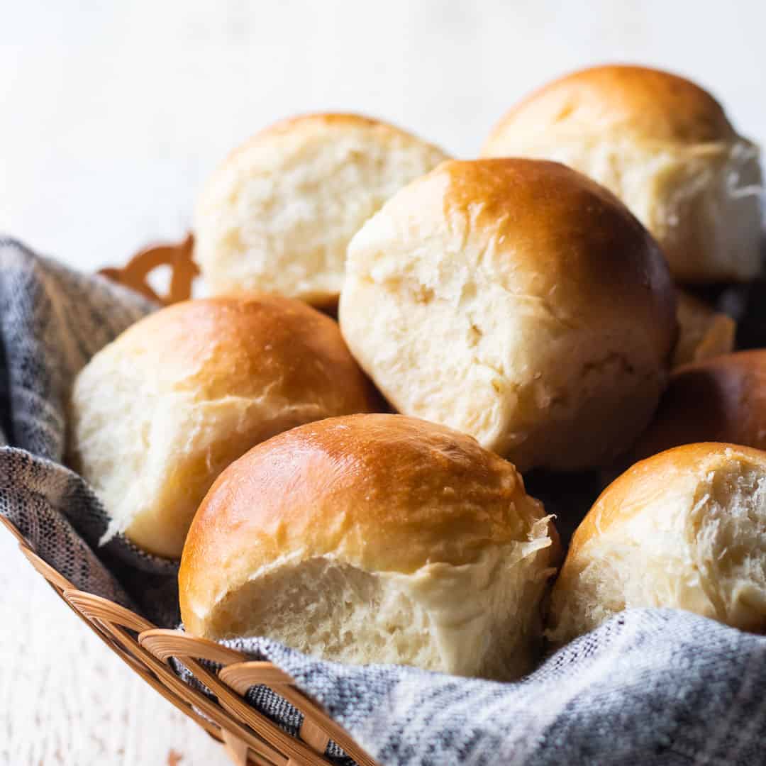 Close up image of a basket of freshly baked soft dinner rolls.