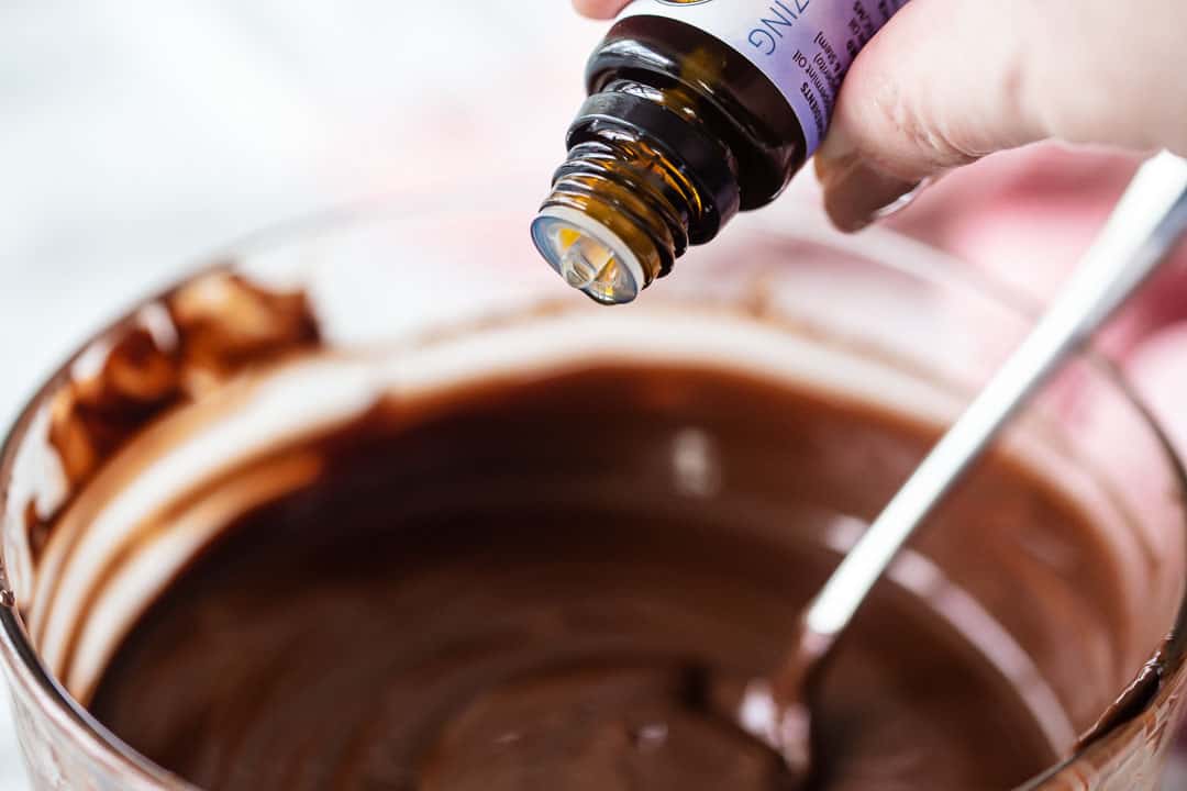 Adding peppermint essential oil to melted chocolate to flavor it.
