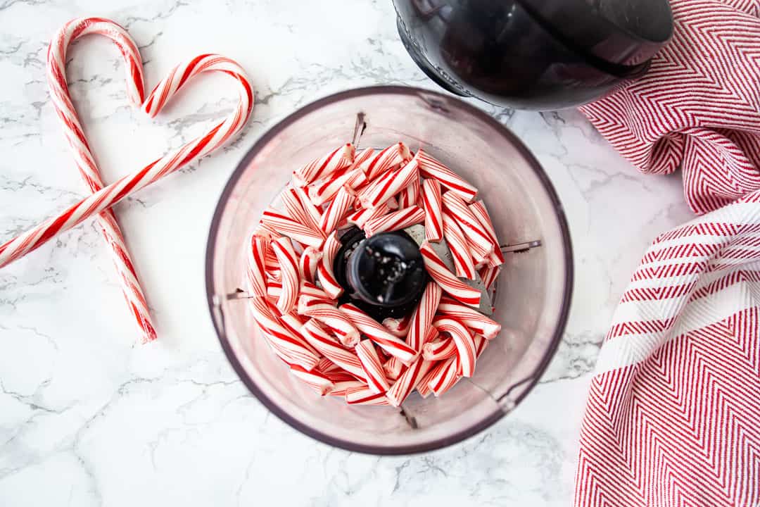 Broken candy canes in the bowl of a small food processor.