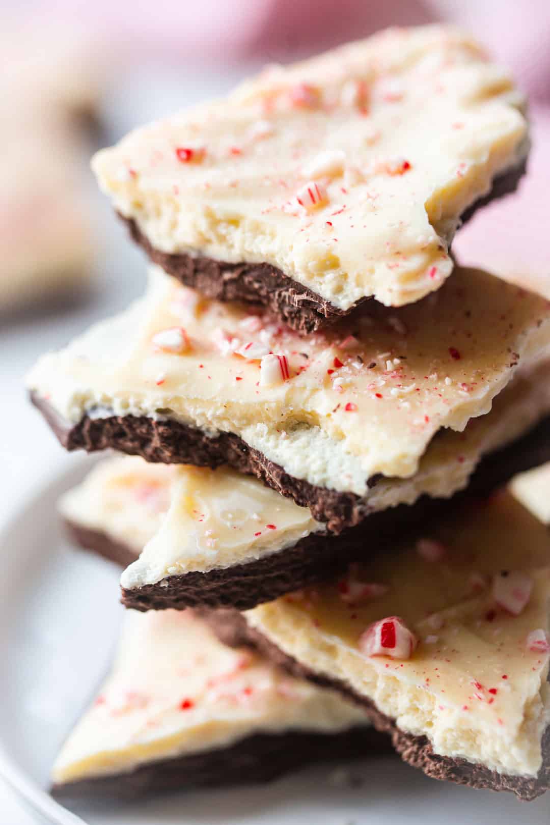 Homemade Ghirardelli peppermint bark, stacked on a white porcelain plate.