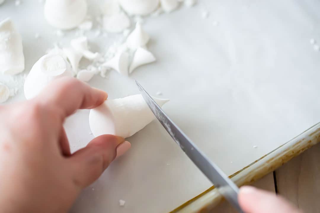 Trimming meringue mushrooms with a sharp paring knife.