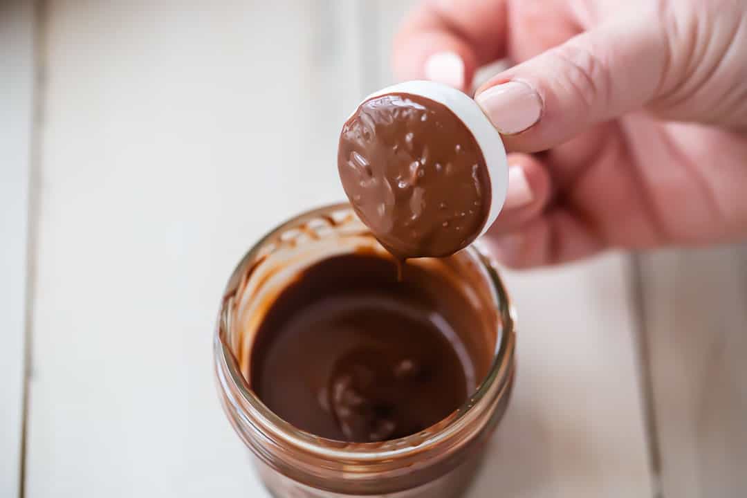 Dipping meringue mushroom caps into melted chocolate.