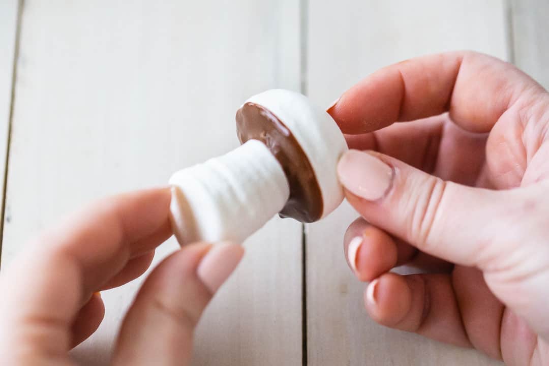 Attaching meringue mushroom stems to caps with melted chocolate.