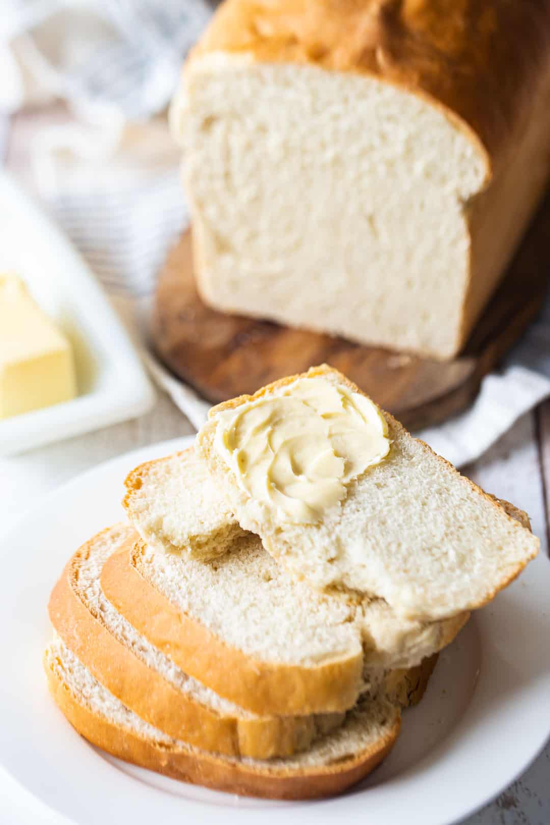 Sandwich bread sliced and stacked on a white plate.