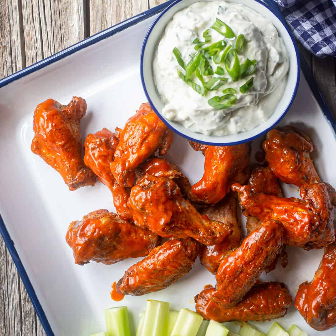 Chicken wings baked crispy & coated in spicy buffalo sauce, served on a tray with blue cheese dressing and celery sticks.