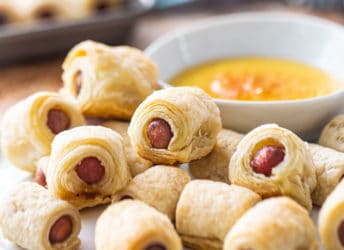 Pigs in a blanket on a plate with honey mustard dip.
