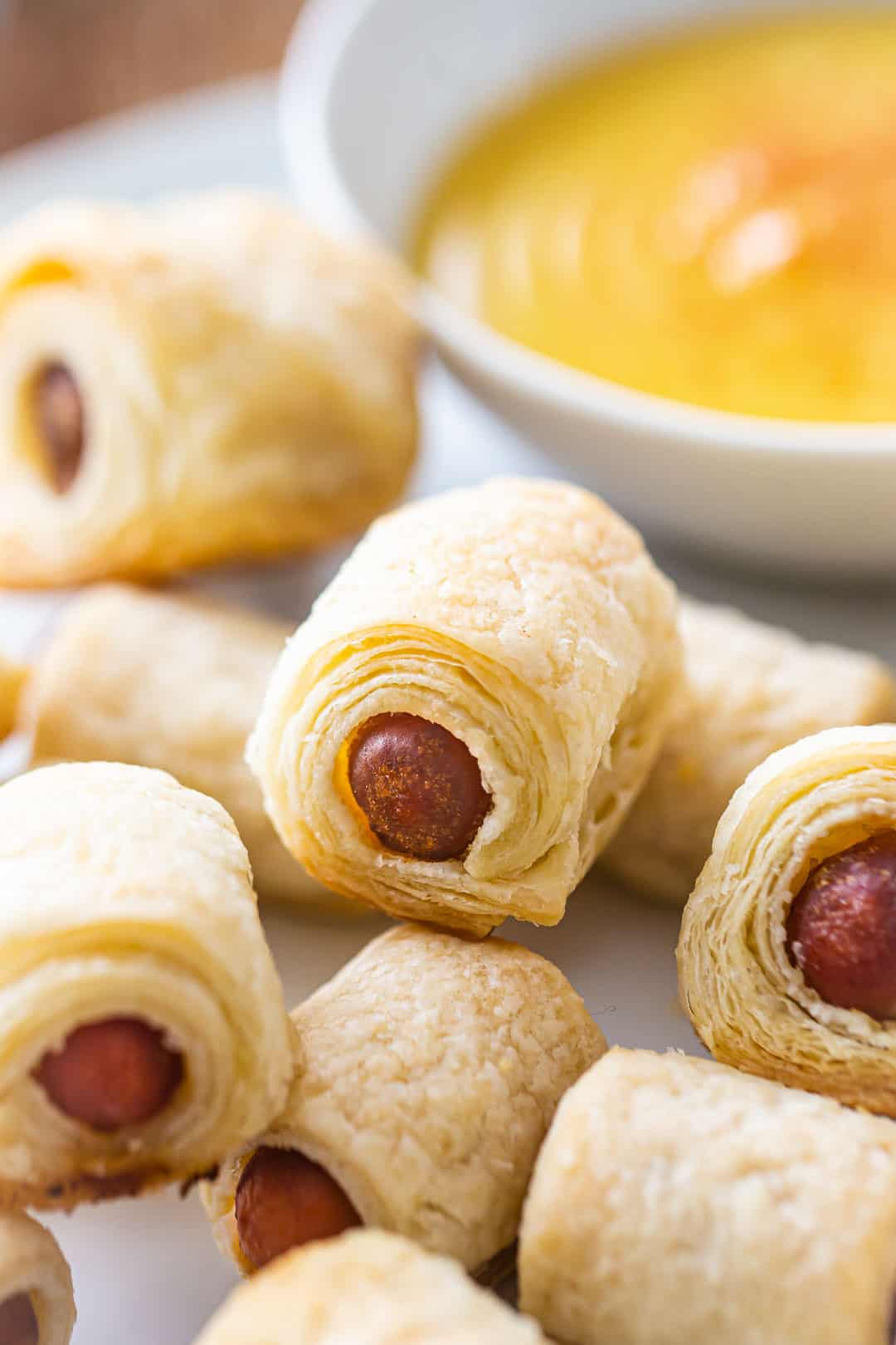 Close up image of mini pigs in a blanket, showing the many flaky layers of the homemade puff pastry.