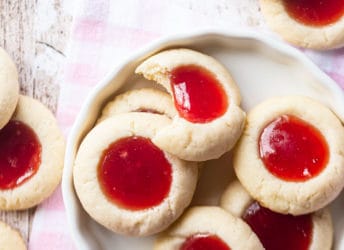 Thumbprint cookies in a white ceramic dish with a pink gingham cloth.