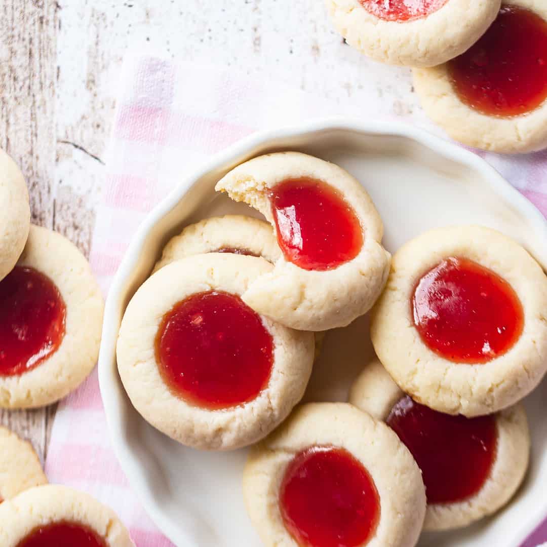 Thumbprint cookies in a white ceramic dish with a pink gingham cloth.