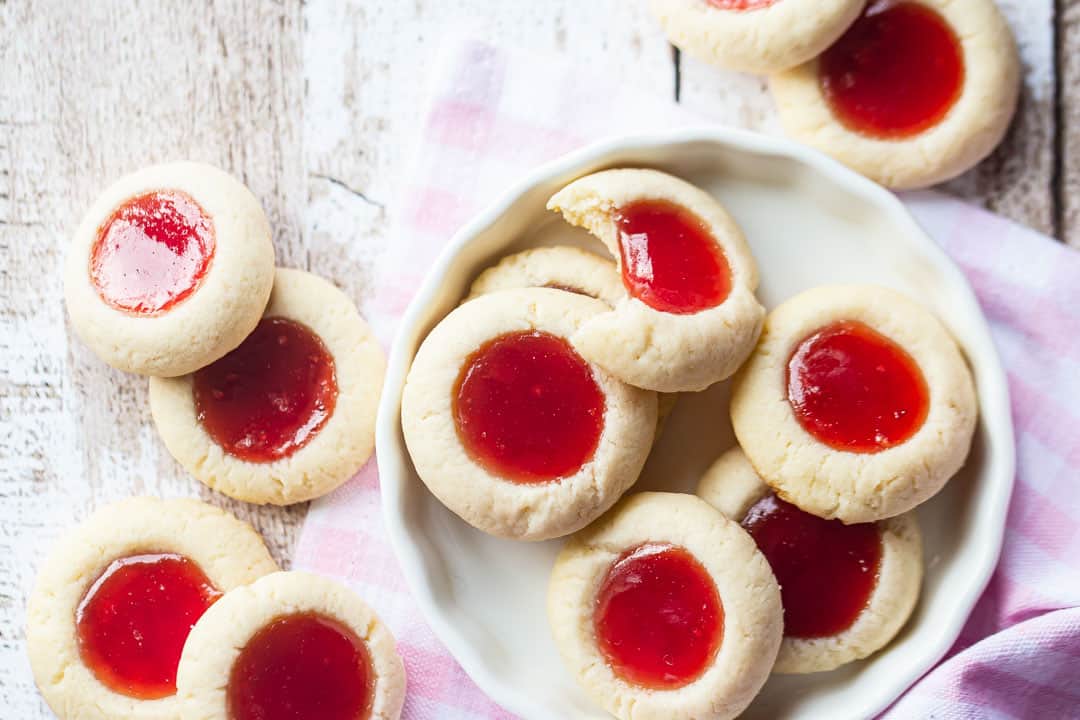Raspberry thumbprint cookies on a distressed wood background.