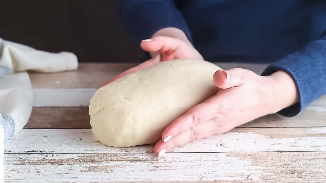 Forming white bread dough into a loaf shape.