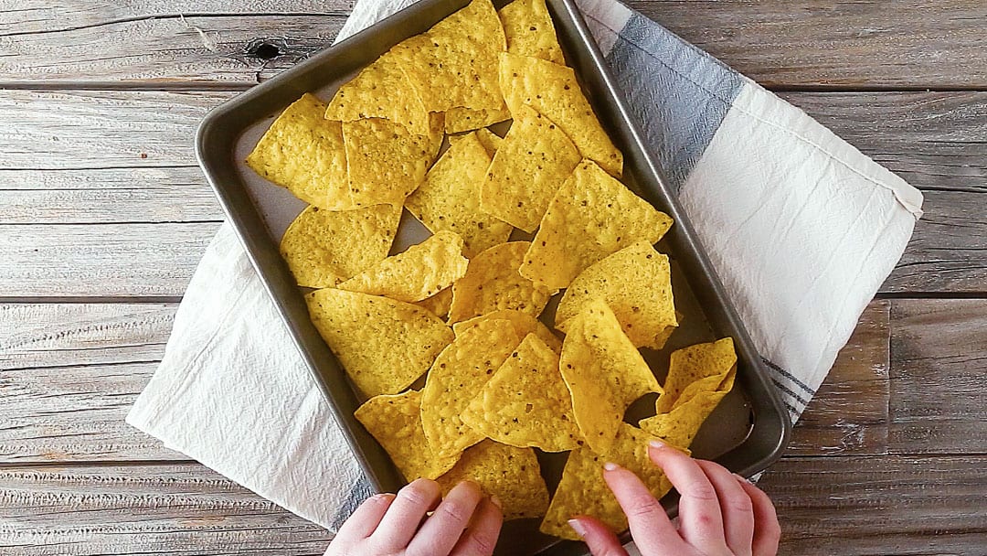 Arranging tortilla chips on a sheet pan for nachos recipe.