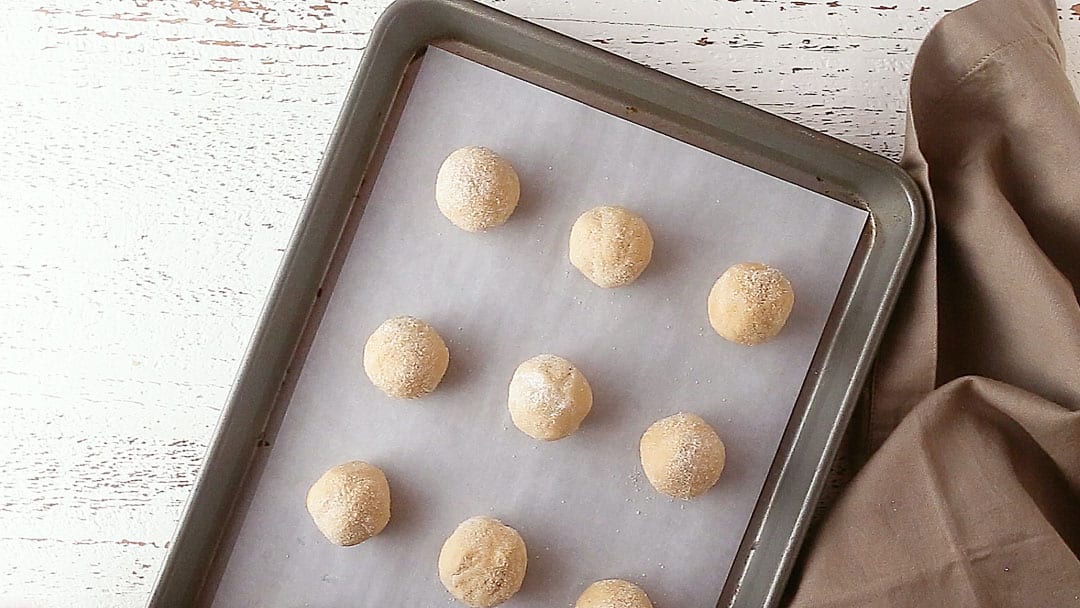 Unbaked peanut butter blossoms on a parchment-lined baking sheet.