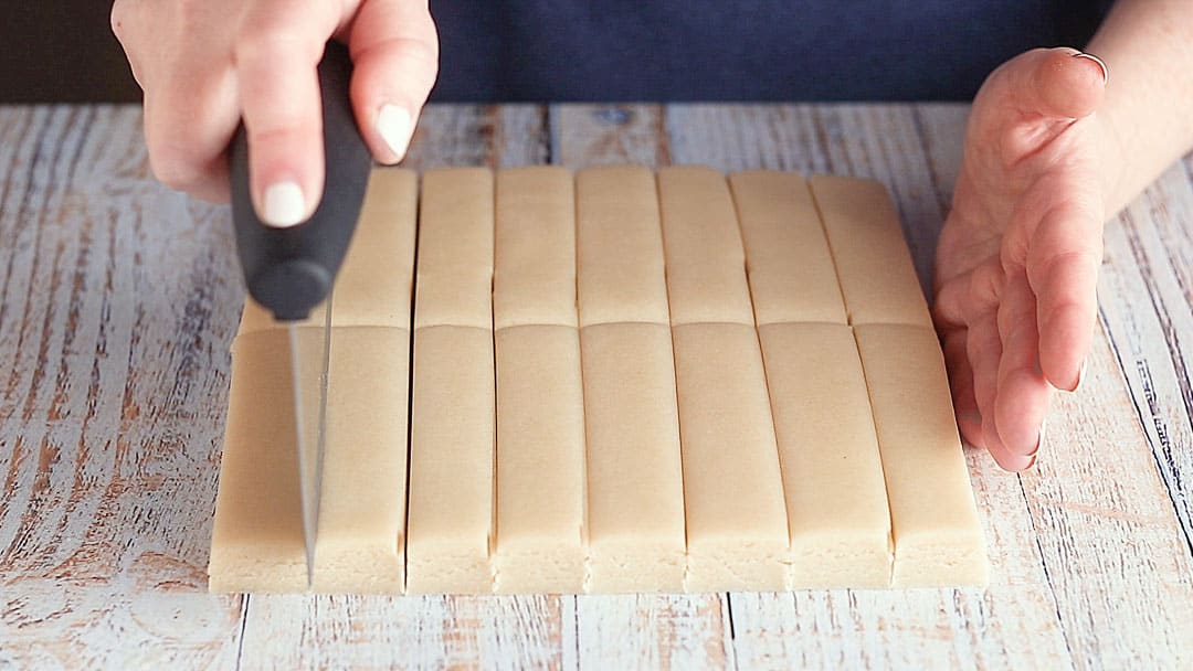 Cutting shortbread cookies into bar shapes.