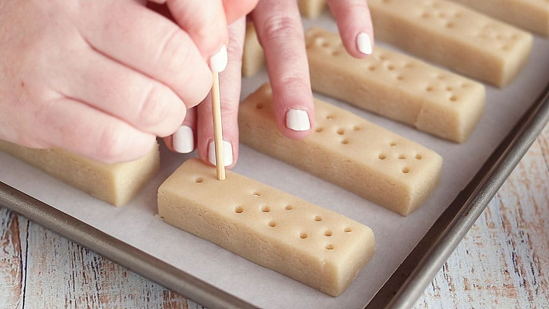 Docking shortbread cookies with a bamboo skewer.