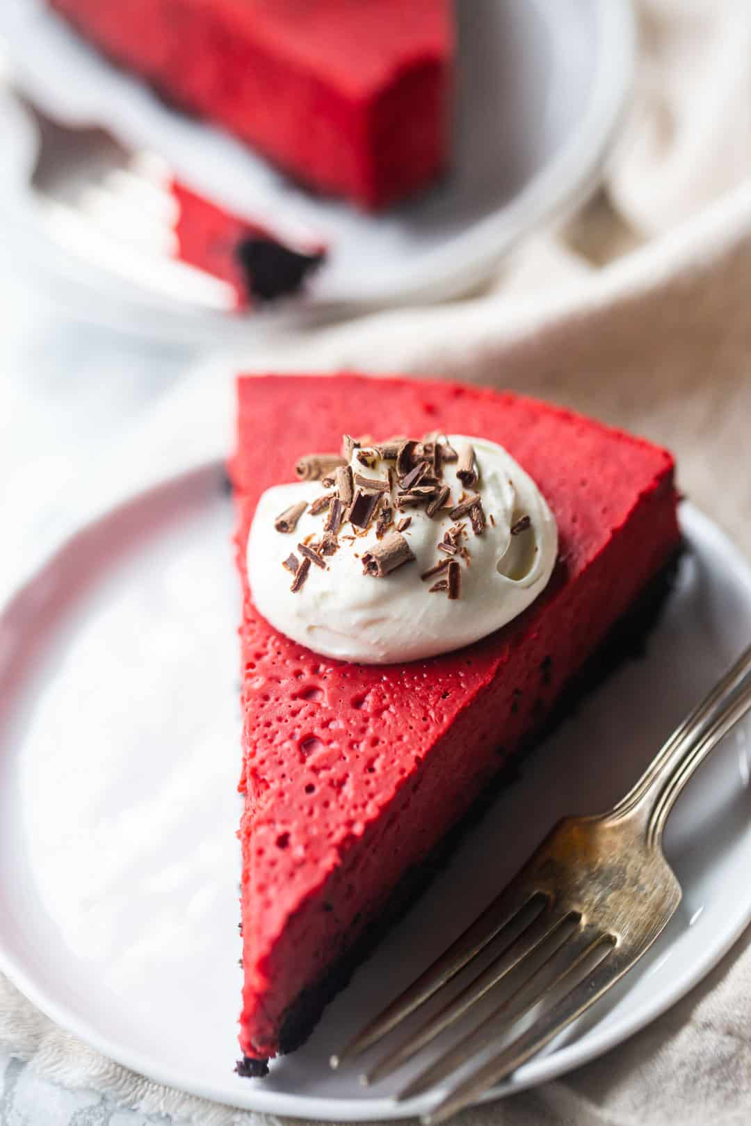 Cheesecake factory red velvet cheesecake copycat recipe, served with whipped cream and chocolate shavings.