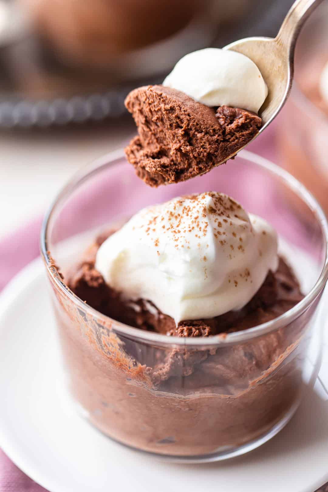 Spooning easy chocolate mousse recipe from a glass bowl with a silver spoon.
