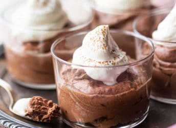 Small glass bowls of chocolate mousse with whipped cream on an antique silver tray.