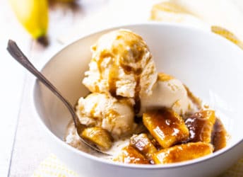Bananas Foster in a white bowl with vanilla ice cream.