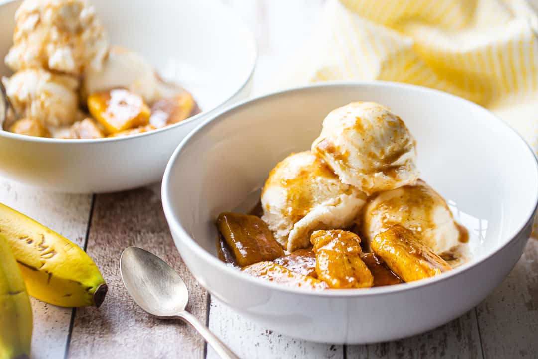 What is bananas Foster in a white bowl over vanilla ice cream.