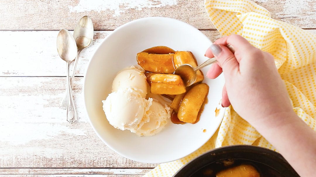 Spooning bananas Foster into a serving bowl.