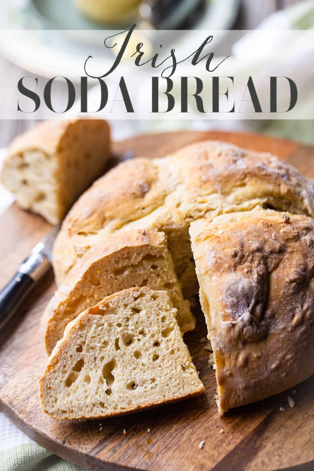 Soda bread sliced and served with butter on a wooden board, with a text overlay above that reads "Irish Soda Bread."