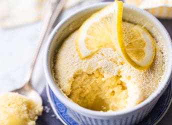 Lemon pudding cake in a ramekin with a lemon twist on top.