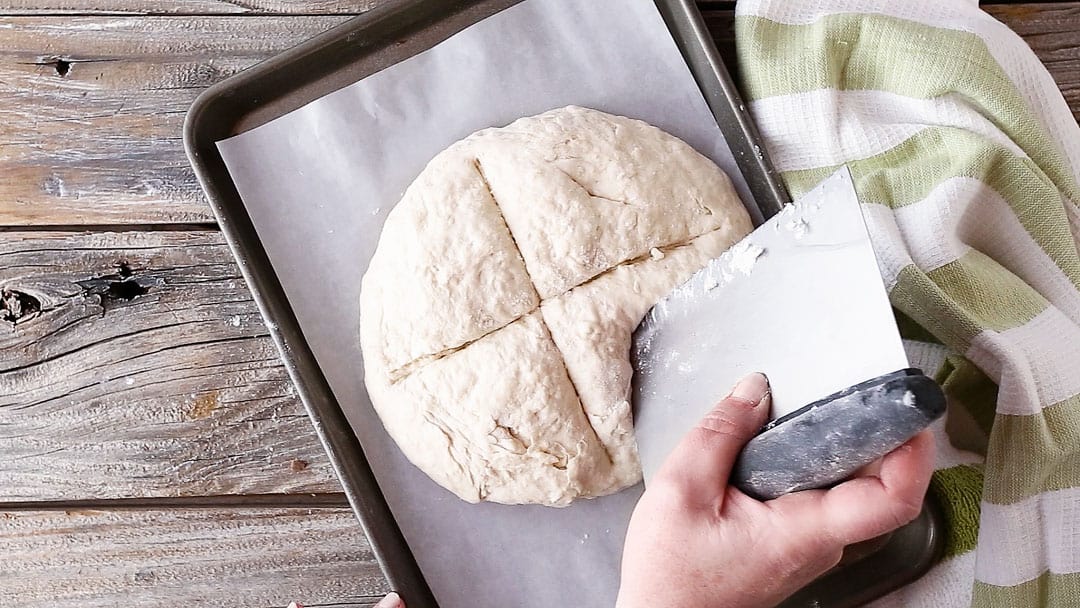 Piercing Irish soda bread with the tip of a knife.