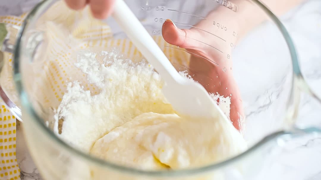 Folding lemon pudding cake batter gently.