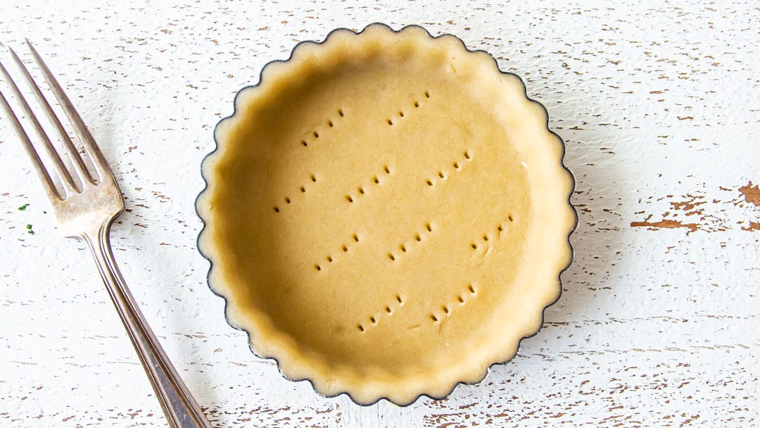 Docking mini tart dough with a fork to allow air to escape.