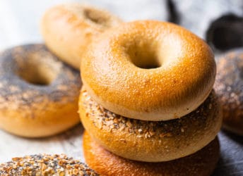 Bagel recipe, baked and served on clean newspaper, with plain, poppy seed, sesame seed, and everything bagels shown.