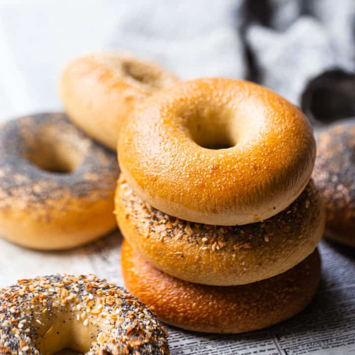 Bagel recipe, baked and served on clean newspaper, with plain, poppy seed, sesame seed, and everything bagels shown.