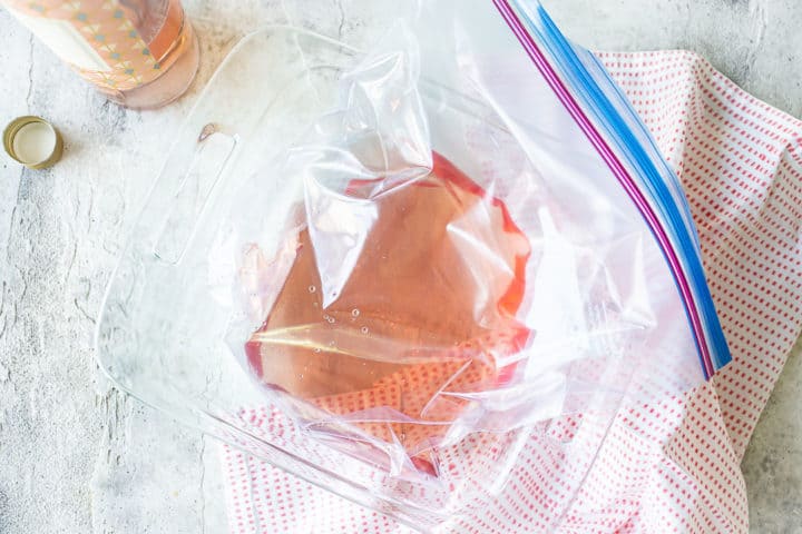 Rosé wine in a freezer bag placed in a square glass baking dish.
