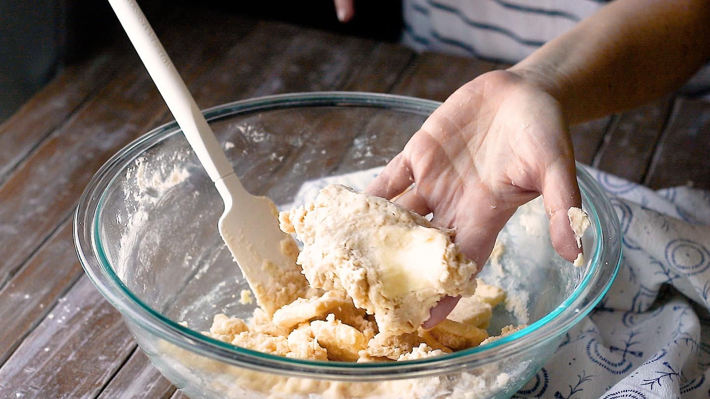 Squeezing fresh made pie dough with your hand to see if it holds together.