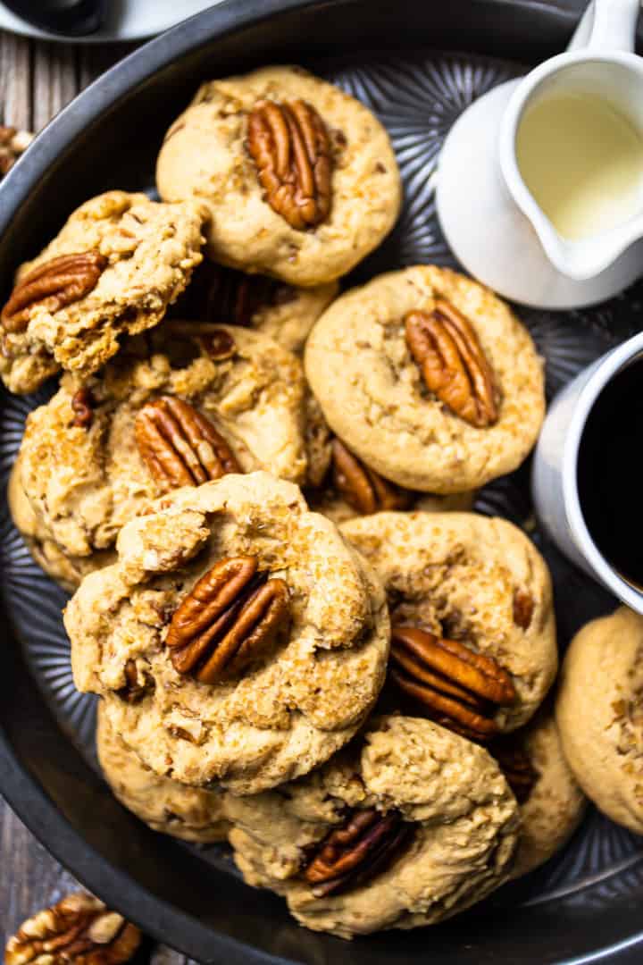 Close-up overhead image of brown butter cookies with pecans, piled into a pie dish.