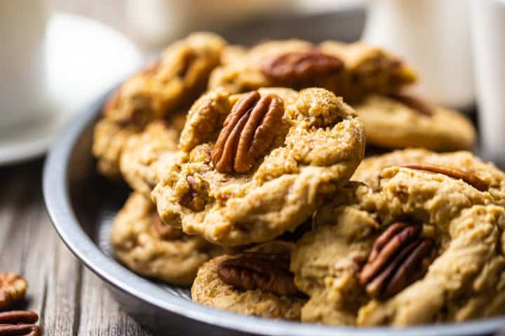 Extreme close-up of pecan cookies in a dish, garnished with coarse sugar and whole pecan halves.