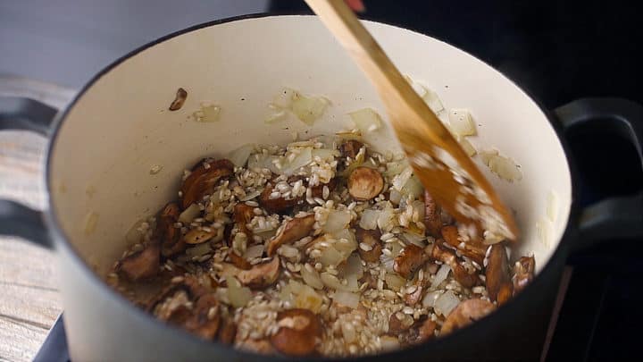 Cooking onion, mushrooms, and arborio rice together in a large pot.